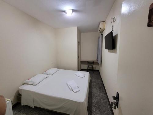 Cette petite chambre comprend un lit blanc et une télévision. dans l'établissement BIGS HOTEL, à Penápolis
