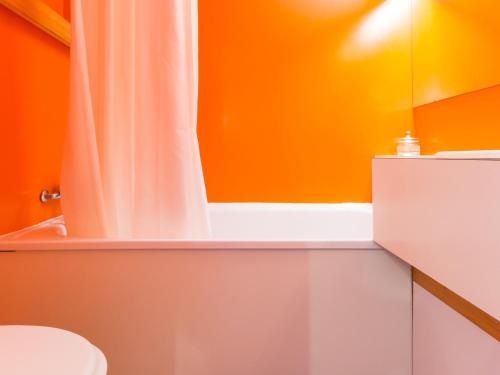 une salle de bain orange avec un rideau de douche et des toilettes dans l'établissement Studio lumineux proche centre avec balcon - FR-1-346-445, à Arc 1800