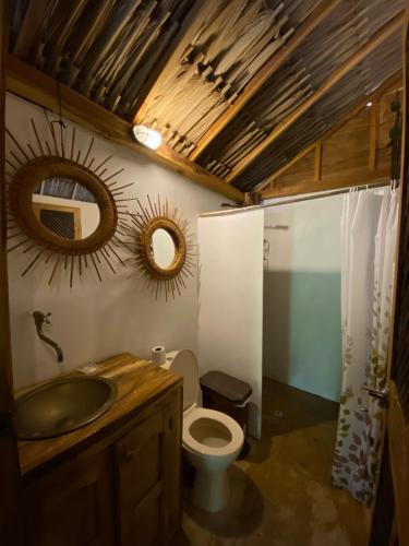 y baño con aseo, lavabo y espejos. en Cabañas roble verde, en Rincón