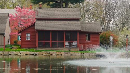a red house with a fountain in front of a pond at Whimsical Cottage w/ Pond View in Dundee