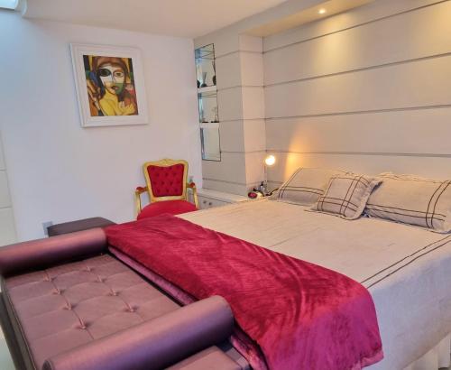 1 dormitorio con 1 cama grande y 1 silla roja en Palace Residence, en Garanhuns