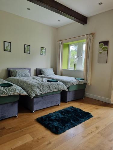 two beds in a bedroom with a window and a rug at Lakeside cottage in Huddersfield