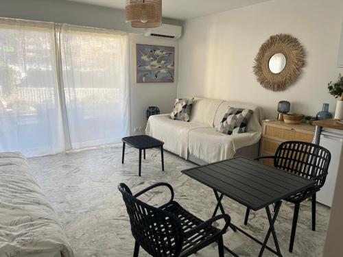 uma sala de estar com um sofá, uma mesa e cadeiras em Studio cosy avec terrasse sur la plage em La Seyne-sur-Mer