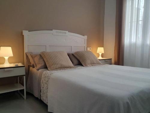 a bedroom with a large white bed with two lamps at Edif Sanctipetri in Novo Sancti Petri