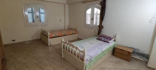 two beds in a room with two windows at شاليه ٢٩ لا ارضي غرفتين اللوتس الساحل الشمالى in El Alamein