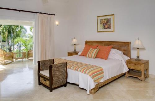 a bedroom with a bed and a chair and a window at Sunny Vacation Villas No 14 in Saint Peter