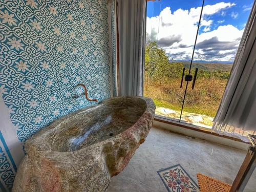 a bathroom with a large tub in front of a window at Mirante do Espinhaço in Itabirito