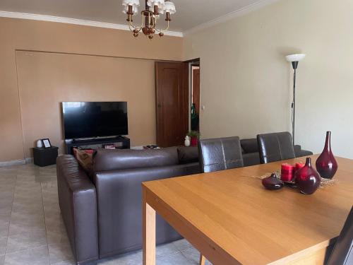 a living room with a leather couch and a table at Cozy apartment near Parque das Nações in Bobadela