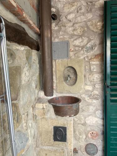 Una pared de piedra con un cubo de cobre. en Da Valentino e Manuela en Barberino di Mugello