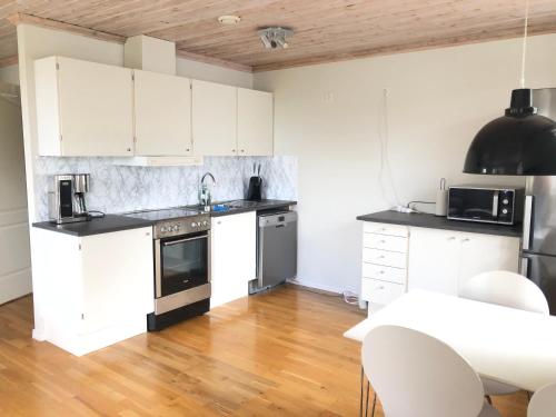 uma cozinha com armários brancos e uma mesa e cadeiras em GG Village em Askim