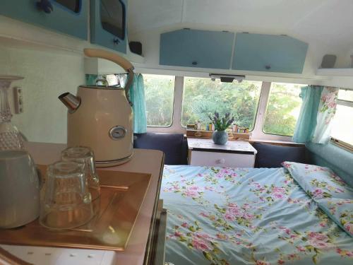 a room with a kitchen and a bed in a caravan at Cosy private Glamping with Pizza stove, Big Projector Screen, own hot Monsoon shower, breakfast - Glamping with a difference! in Tenby