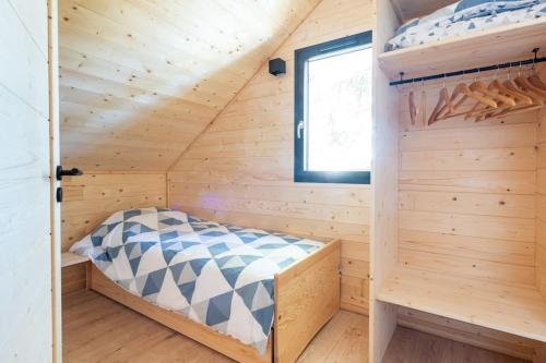 a bed in a wooden cabin with a window at Chalet perché Chabanon - Alpes du Sud in Selonnet
