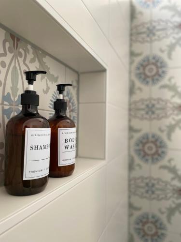 two bottles of soap sitting on a shelf in a bathroom at Bed & Breakfast By Genck in Oudenbosch