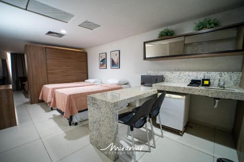 a room with a bed and a table and chairs at Imperial Nobile in Tambaú