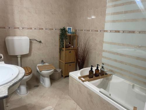 een badkamer met een bad, een toilet en een wastafel bij Cozy apartment near Parque das Nações in Bobadela