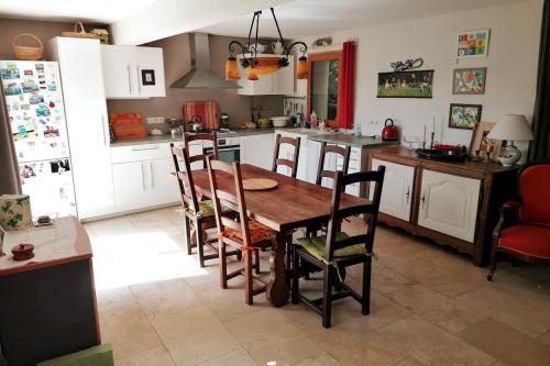 een keuken met een houten tafel en stoelen bij La maison de la vigne in Bauduen