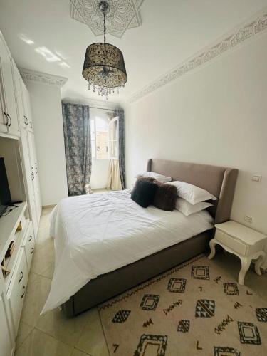 a bedroom with a large bed and a chandelier at Appartement jade in Essaouira