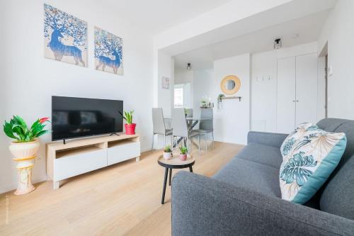 Cosy Appart Proche Paris في مونتروي: غرفة معيشة مع أريكة زرقاء وتلفزيون