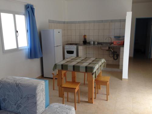 eine Küche mit einem Tisch mit Stühlen und einem Kühlschrank in der Unterkunft Maio Relax in Vila do Maio