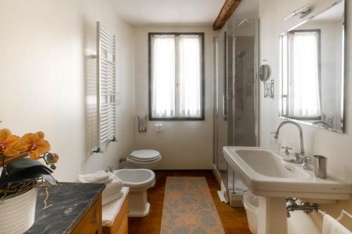 uma casa de banho branca com um lavatório e um WC em Campiello Zen B&B em Veneza