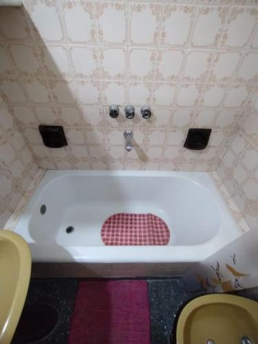 La salle de bains est pourvue d'une baignoire et d'un sol en damier rouge. dans l'établissement CASA ANGELITA en SAAVEDRA, à Buenos Aires
