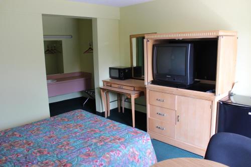 a hotel room with a bed and a tv on a dresser at Travelers Inn Gainesville in Gainesville
