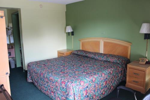 a bedroom with a bed and a dresser and lamp at Travelers Inn Gainesville in Gainesville