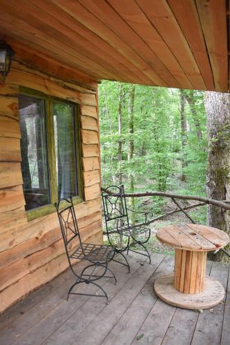 a porch with two chairs and a table on a cabin at La cabane aux écureuils in Philippeville