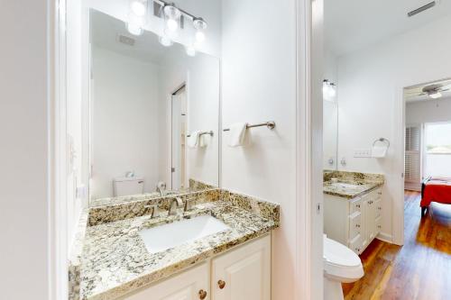 a bathroom with a sink and a mirror and a toilet at Sunset Bay in Dauphin Island
