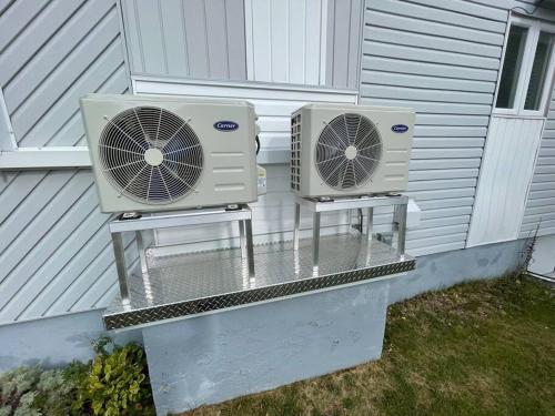 dos acondicionadores de aire sentados en el lateral de una casa en Maison sur le lac, en Desbiens