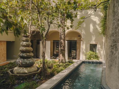 a swimming pool with a fountain in a house with trees at Hotel Palau Fugit in Girona