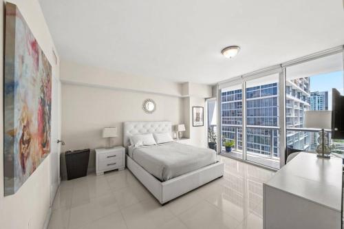 a white bedroom with a bed and a large window at Iconbrickell in Miami