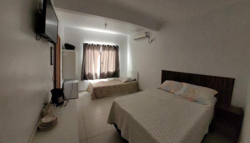 1 dormitorio con 2 camas y TV. en Vó Paulina suites, en Penha