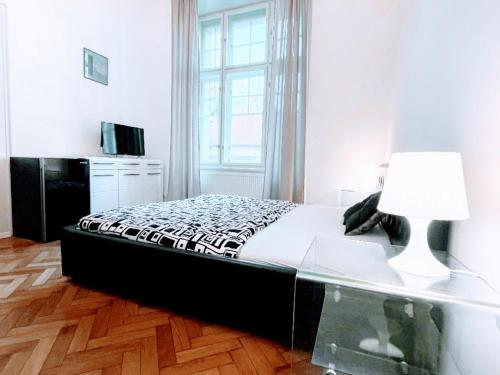 um quarto com uma cama e uma mesa com um candeeiro em Black & White Flat for 2 / Peaceful / Jewish Quarter em Praga