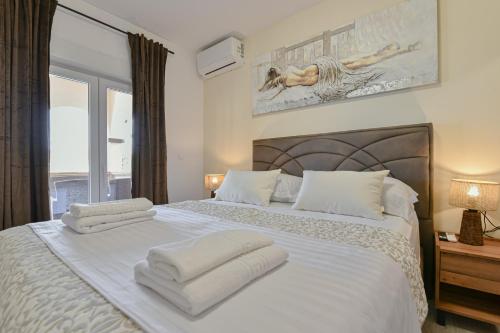 a bedroom with a white bed with towels on it at Bralic Residence in Bibinje