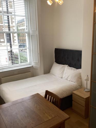 Schlafzimmer mit einem Bett, einem Fenster und einem Tisch in der Unterkunft Central London Rooms in London