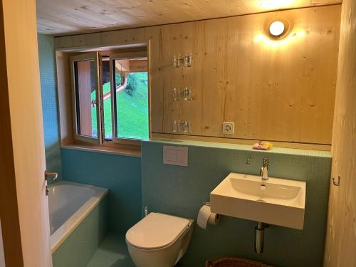 a bathroom with a sink and a toilet and a tub at Sunnehuesli in Braunwald