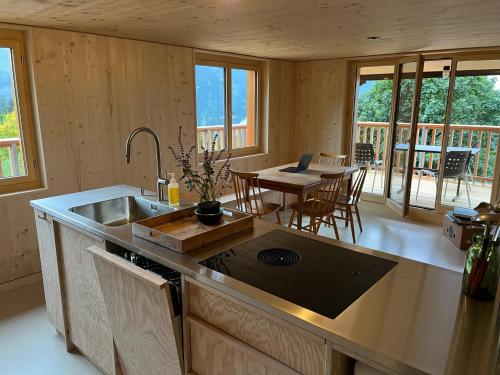 eine Küche mit einem Waschbecken und einem Tisch mit Stühlen in der Unterkunft Sunnehuesli in Braunwald