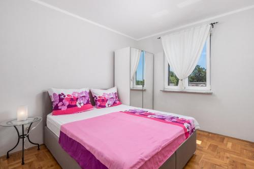 1 dormitorio con cama rosa y ventana en Apartments Bugenvila Brzac, en Brzac