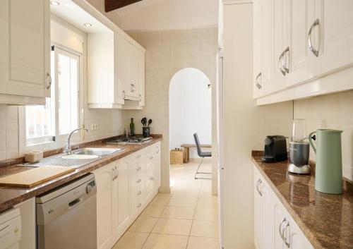 a kitchen with white cabinets and a counter top at Villa with pool and hot tub on golf course in Altea