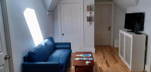 a living room with a blue couch and a table at Guest suite in historical district in Gloucester