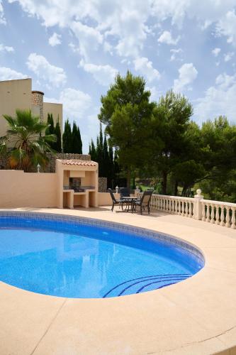 a large swimming pool in a yard with a patio at Villa with pool and hot tub on golf course in Altea