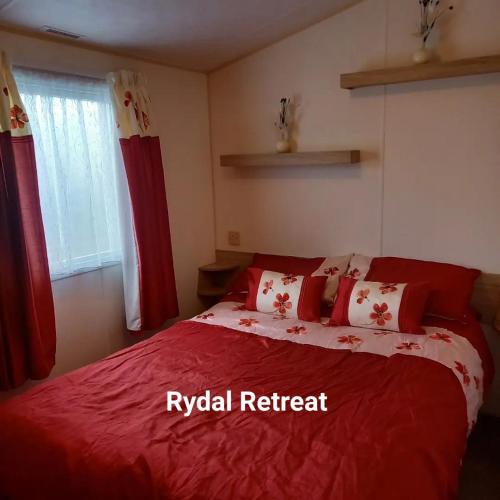 a bedroom with a red bed with red and white pillows at Rydal Retreat Lakeland Holiday Park in Flookburgh