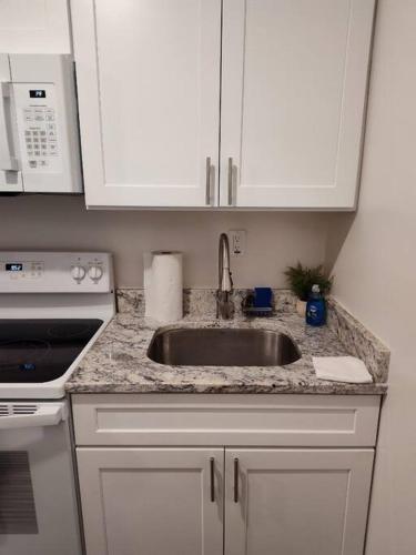 a kitchen with a sink and a stove and white cabinets at Serene Studio Apt in Gadsden AL in Gadsden