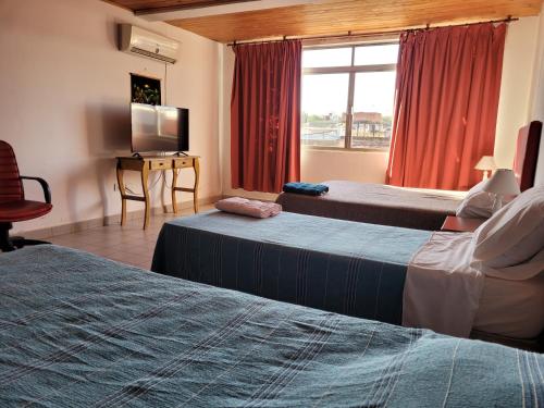 una camera d'albergo con due letti e una televisione di Iguazu House a Puerto Iguazú