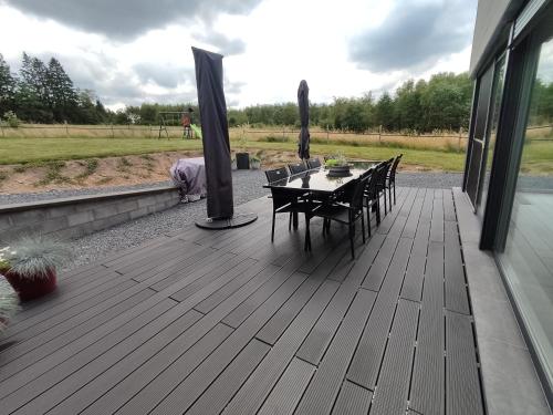 a wooden deck with a table and chairs on it at À l'orée de la Fôret in Manhay
