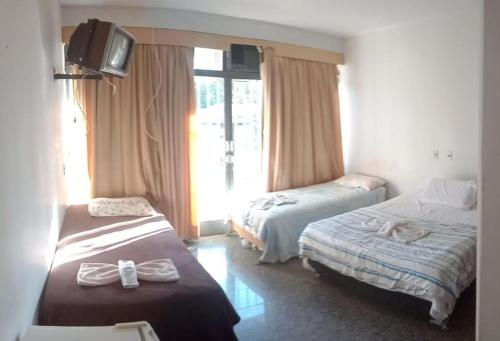 ブラジリアにあるBeiruth Hotelのベッド2台とテレビが備わるホテルルームです。