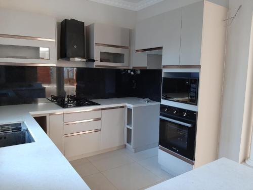 a kitchen with white cabinets and black appliances at Royal Feather in Tirunelveli East