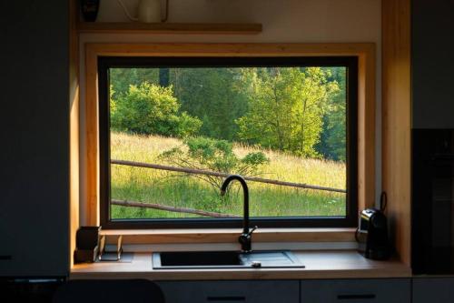 a window over a kitchen sink with a view of a field at Domek z sauną Neptun in Krzyżowa
