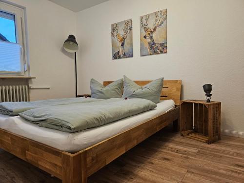 1 dormitorio con cama de madera y 2 cuadros en la pared en Deisterquartier, Ferienwohnung am Naherholungsgebiet, en Barsinghausen